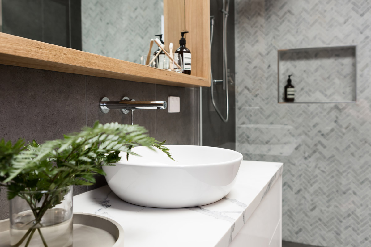 vanity unit with large wood framed mirror and modern tiling in a new bathroom